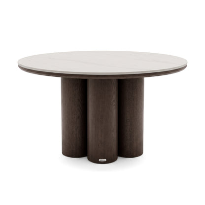 Round dining table with light top and dark cylindrical base on white background