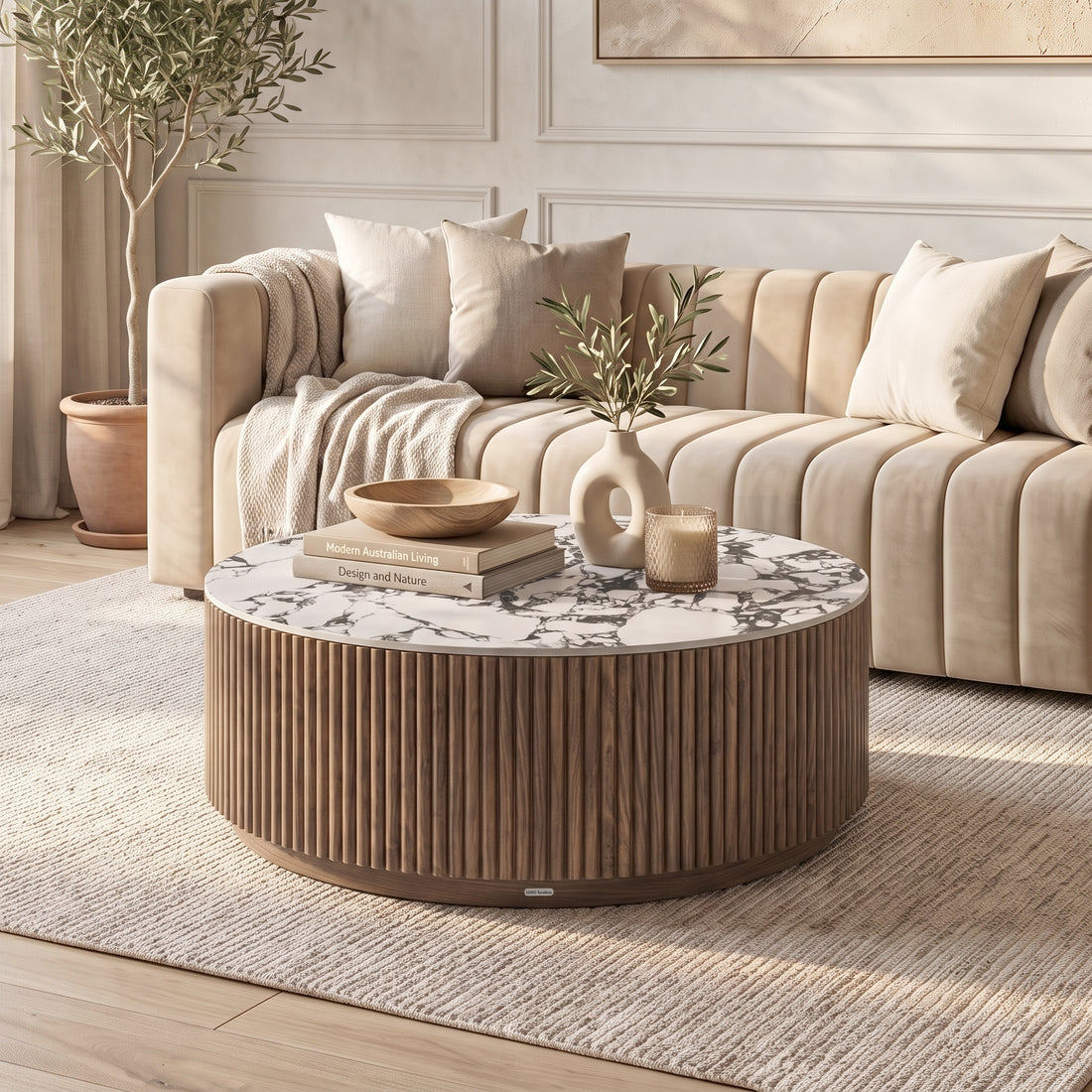 Round coffee table styled in a modern living room with sofa, cushions, plant, and decor