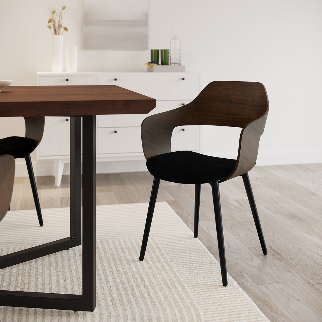 Winfield Curved Wooden Back Velvet Dining Chair Black Set of 2, showcasing upholstered velvet seats and curved wooden backs, next to a table on an indoor floor with visible chair legs.