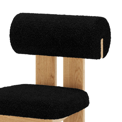 Close up of Wylie Boucle Oak Dining Chair Black Set of Two, featuring plush boucle upholstery, wooden legs, and a cushioned seat for modern dining comfort