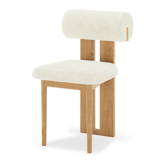 Close-up of Wylie Boucle Oak Dining Chair, showcasing plush boucle fabric on cushioned seat and backrest, with solid oak frame and paneled legs, highlighting elegant and comfortable dining seating.