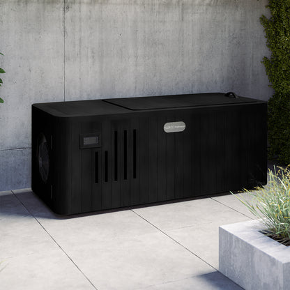 Lambert 2-Person 1HP Chiller Ice Bath in Black, featuring a closed slatted cover, control panel, and vented openings, sits on a gray tiled patio with a planter and climbing vines nearby.