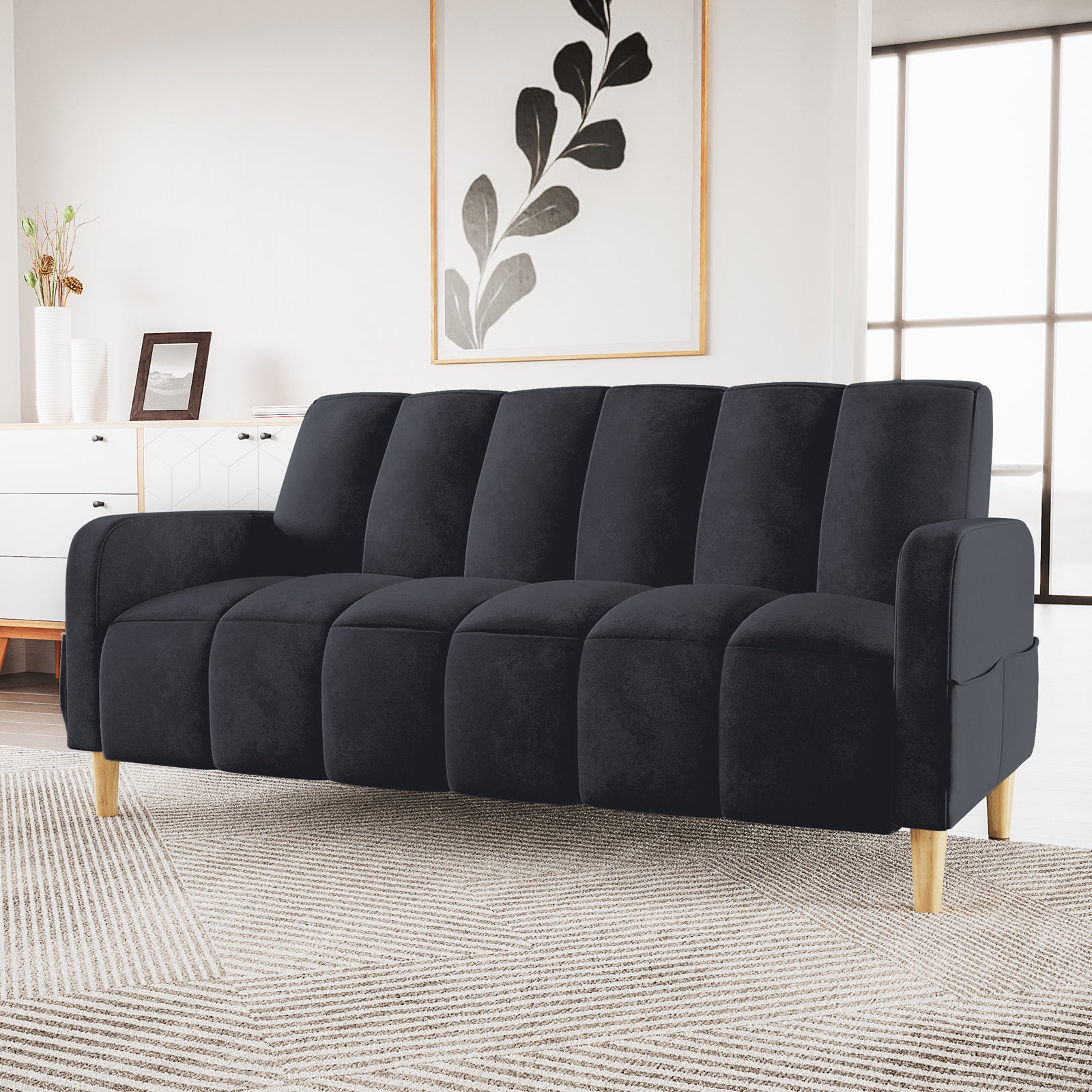 Anica 3 Seater Velvet Sofa Bed in Black, featuring channel-tufted design and light wooden legs, sits in a minimalist living room, complemented by a geometric rug and natural light from a tall window.