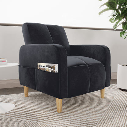 Anica Single Seater Velvet Sofa Chair in Black with rounded arms, divided cushions, light-wood tapered legs, and a side magazine pocket, set on a striped rug beside a white table.
