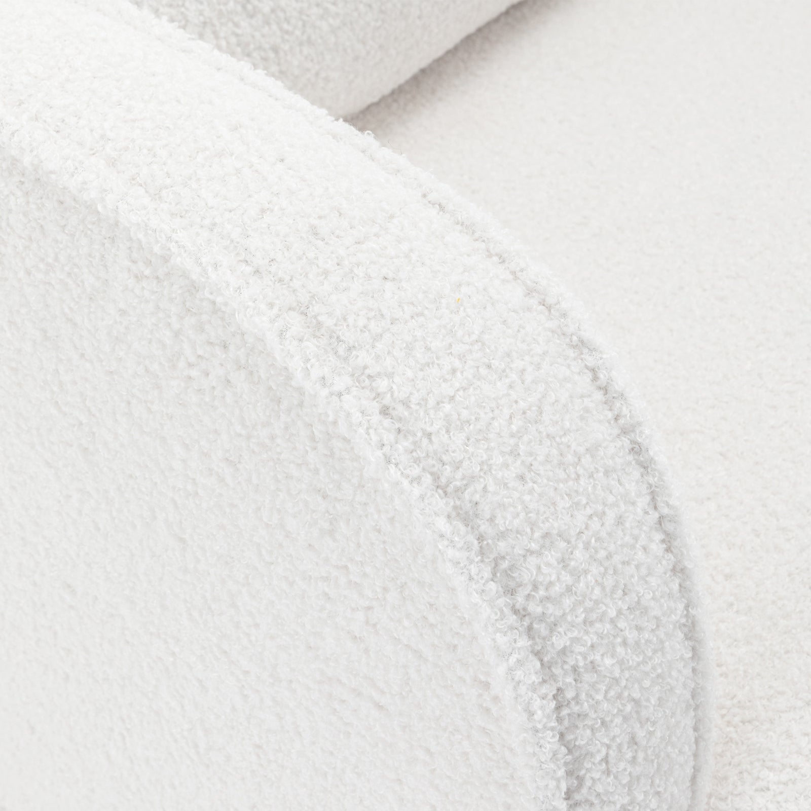 Close-up of Aura Bouclé Rocking Chair with Ottoman in Cream White, showcasing its rounded armrest and seat cushion upholstered in soft, textured bouclé fabric, representing modern elegance and comfort.