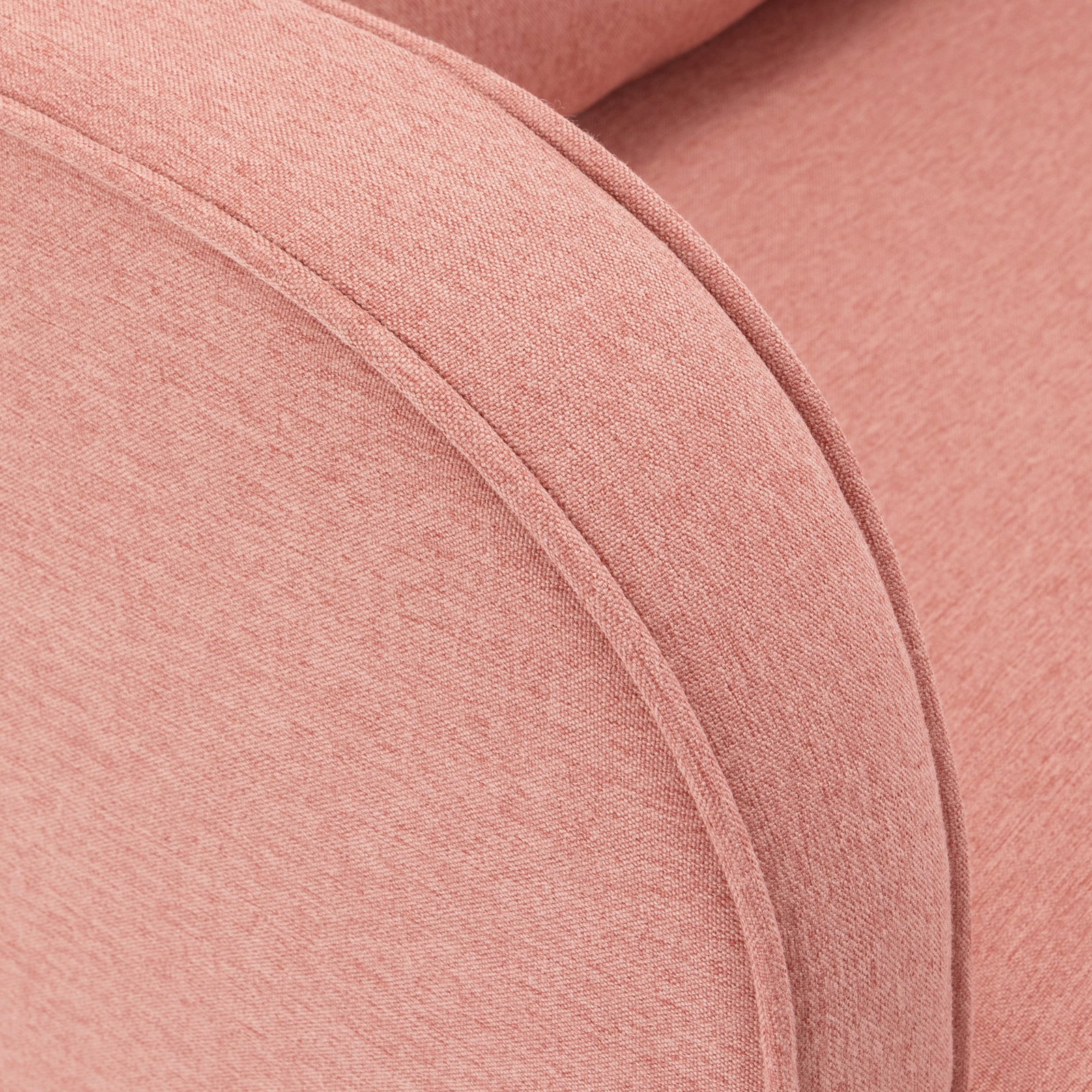 Close-up of the Aura Linen Rocking Chair with Ottoman in Light Pink, showcasing its upholstered arm in soft pinkish-coral fabric with visible piping along the curved edge.