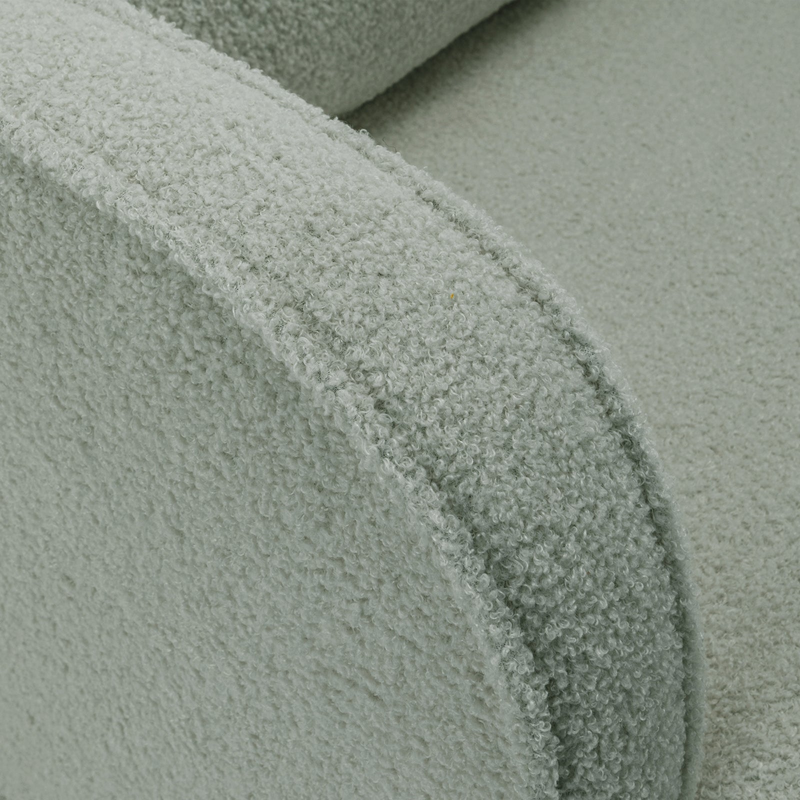 Close-up of Aura Boucle Rocking Chair with Ottoman in Mint Green, showcasing the curved armrest and seat cushion in soft bouclé fabric, emphasizing its cozy and inviting texture and design.