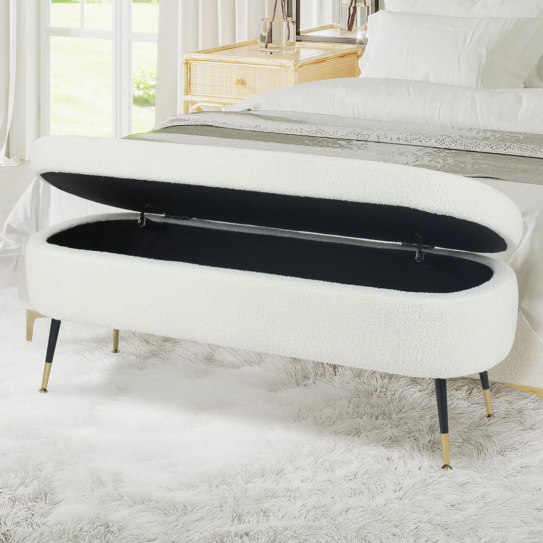 Bella 114cm Boucle Ottoman with Storage in Cream White, featuring an oval shape, white boucle upholstery, hinged top revealing a black interior, and slender black legs with brass-tone feet.