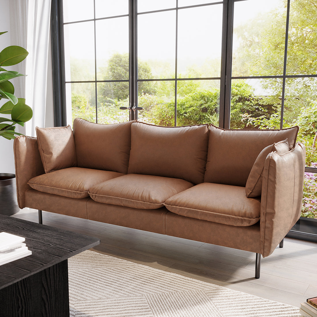 Cassian 3 Seater PU Leather Sofa in chocolate brown, featuring plush cushions, sleek design, and sturdy steel legs, set in a modern living room with a dark wood coffee table and lush outdoor view.