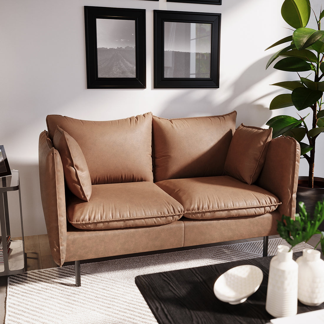 Cassian 2 Seater PU Leather Sofa in Chocolate Brown, with plush cushions, stands in a cozy corner. It’s complemented by black picture frames, a tall houseplant, a black coffee table, and a subtle area rug.
