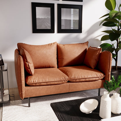 Cassian 2 Seater PU Leather Sofa in Mocha: Warm cognac-brown finish, sleek black metal legs, plush cushions, and side pillows. Complements modern décor with a black-stained coffee table and accent pieces.