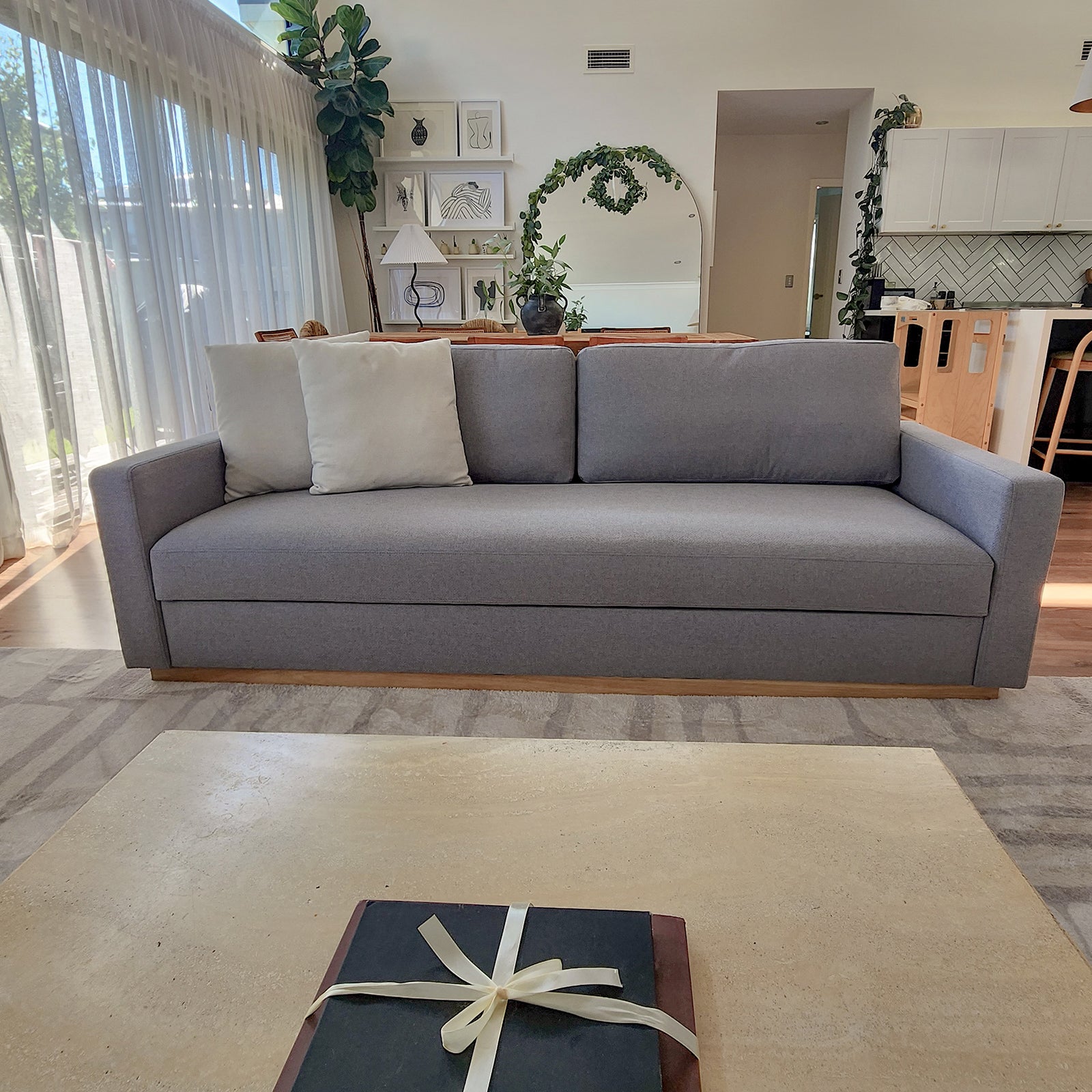 Celeste 3 Seater Hardwood Fabric Sofa Ash on a grey couch with a white pillow, illustrating a modern and stylish design with rubber wood legs for a touch of elegance.