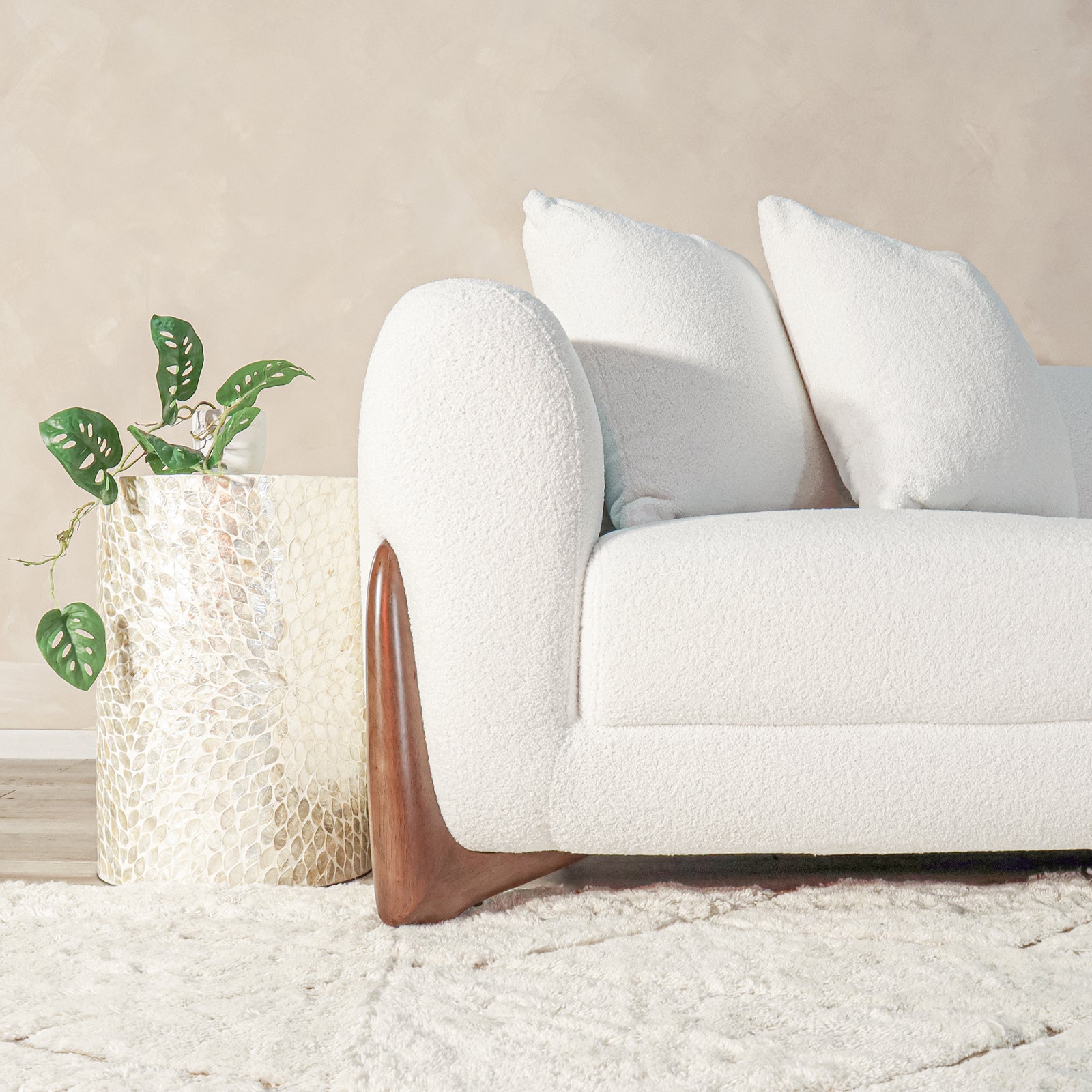 Charla 3-Seater Boucle Sofa with Pillows in Cream White features plush off-white fabric, rounded arms, smooth wood legs, and high-density cushions, creating a cozy, stylish centerpiece in a neutral-toned lounge.