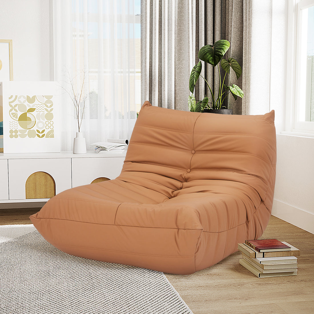Claris PU Leather Tufted Lounge Sofa Chair in Caramel, featuring a low, slouchy design with warm tan leather, positioned in a bright, modern living room corner with light-wood flooring and a media console.