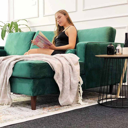 Woman reading on Claude 3 Seater Velvet Sofa with Chaise, featuring a sleek design and plush velvet fabric, comfortably seating three with fixed cushions for stability, ideal for modern interiors.