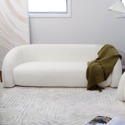 Clioz 3 Seater Curved Boucle Sofa in Eggshell White featured with an olive-green throw, showcasing its plush texture, mid-century design, and spacious seating in a modern living room setting.