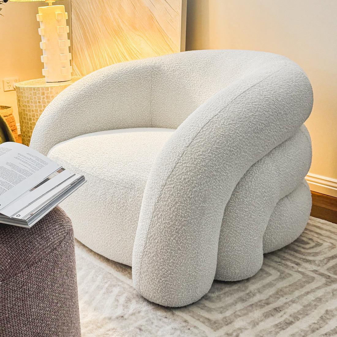 Close-up of the Clioz Boucle Accent Armchair, showcasing its textured boucle fabric and plush cushions, set in a stylish eggshell white finish.
