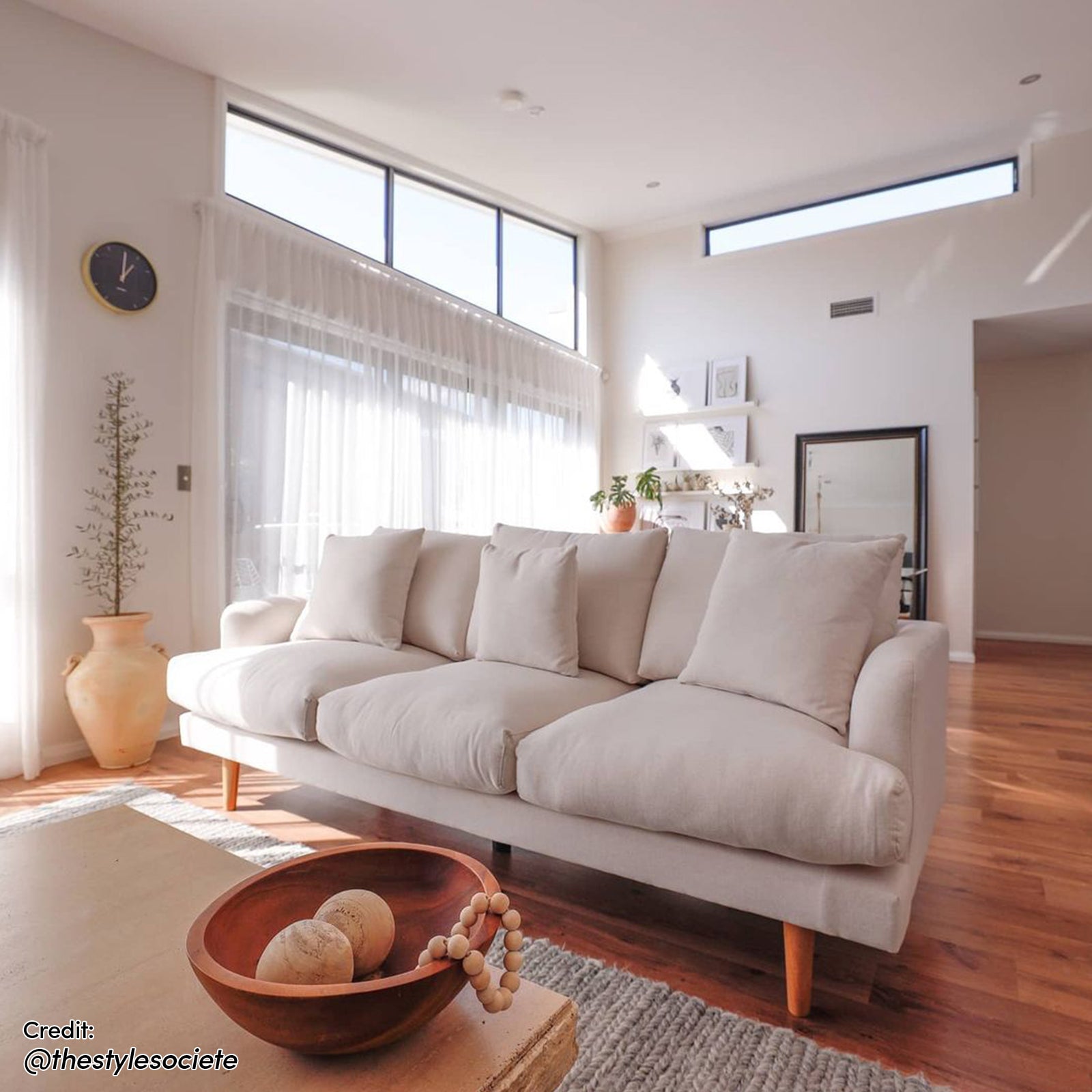 Colton Fabric 3 Seater Sofa Cream White, featuring sleek lines and plush cushions, displayed in an elegant living room setting with a modern indoor plant and stylish pillows.