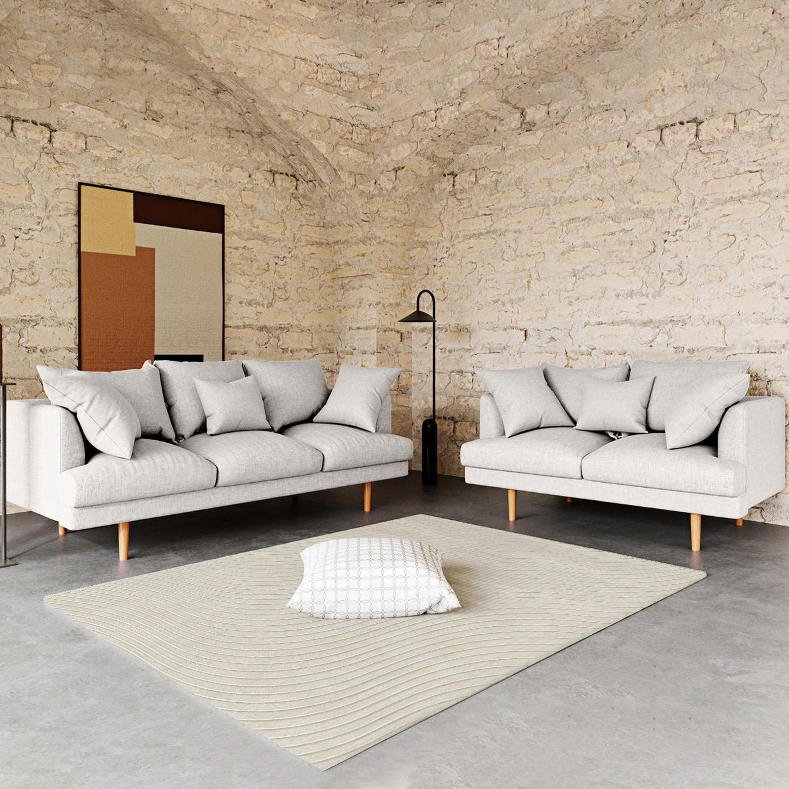 Colton Living Room Package in Cream White featuring two light-gray sofas with accent pillows, a cream-beige rug on concrete, and a black floor lamp, creating a minimalist, industrial-style ambiance.