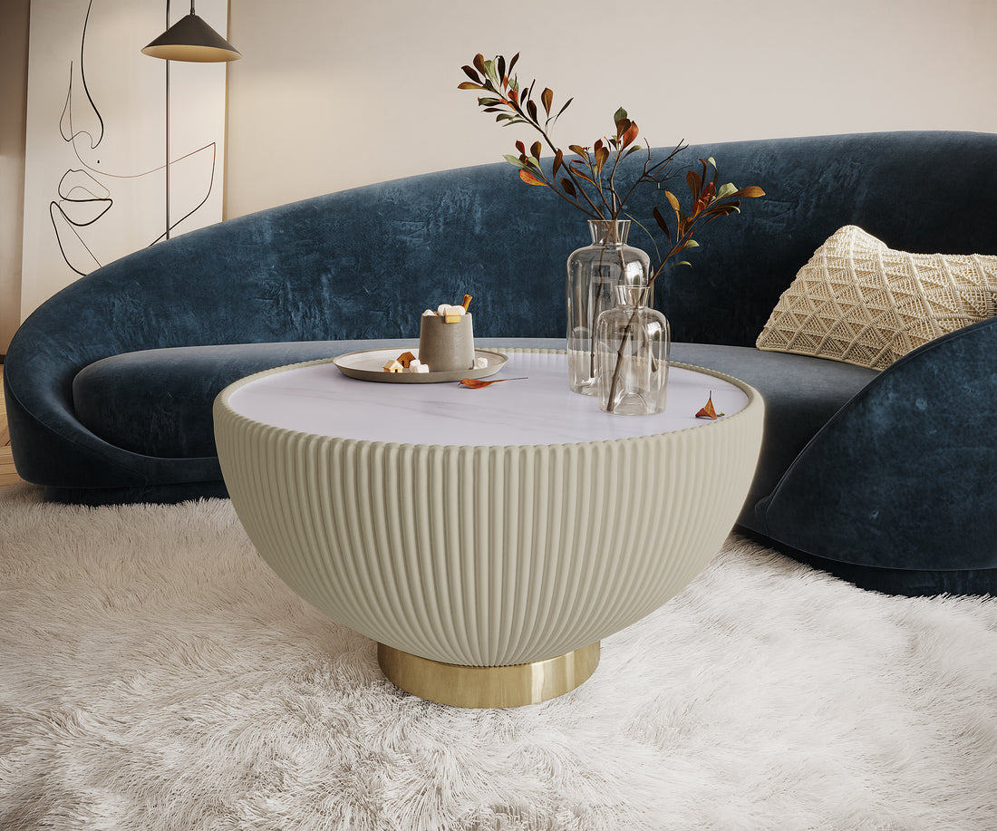 Colton Living Room Package - Cream White features a deep-blue velvet sofa with a cream pillow, a fluted coffee table with brass accents, and clear vases, creating a cozy, modern aesthetic.