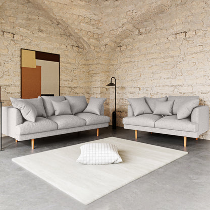 Colton 5-Seater Fabric Sofa in Stone nestled in a minimalist living-room corner with mid-century style, featuring sleek lines and plush cushions, complemented by a black floor lamp and abstract artwork.