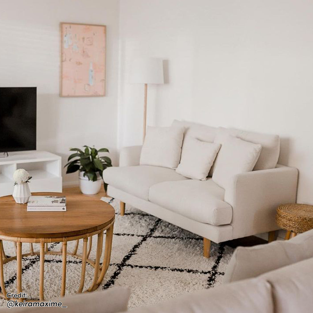 Colton 2 Seater Fabric Sofa Cream White in a modern living room, featuring sleek design, two back cushions, and three throw pillows, complemented by a wood floor and coffee table for added style.