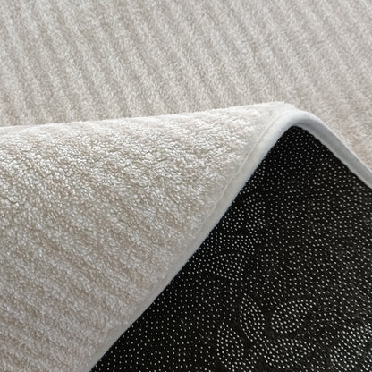 Close-up of the Colton 2 Seater Sofa with Rug in Cream White Fabric, showing a soft, white loop-pile rug with a black, non-slip backing featuring gripper bumps.