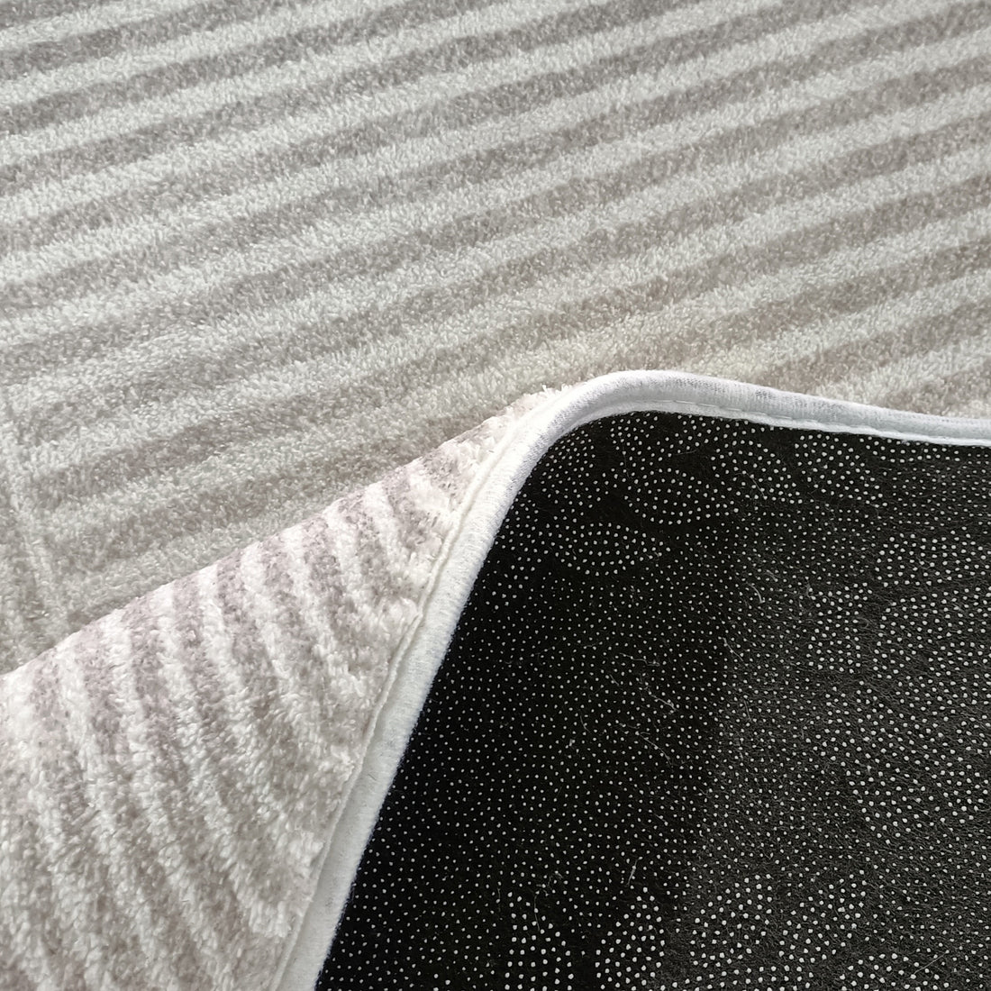 Close-up of Colton 2 Seater Fabric Sofa with Rug - Cream White, highlighting the modern abstract floor rug's white, low-pile surface and black, dotted, non-slip backing, complementing contemporary interiors.