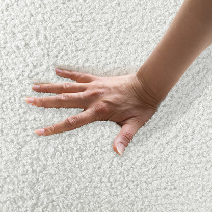 A hand presses into the soft, loop-textured surface of the Corina 3 Seater Modular Boucle Sofa in Cream White, highlighting its luxurious, plush texture and elegant design.