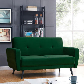 Esben 2-Seater Velvet Sofa Bed in Forest Green, featuring subtle button-tufting and angled black legs, set in a modern living room with a dark wall, framed prints, and a window view.