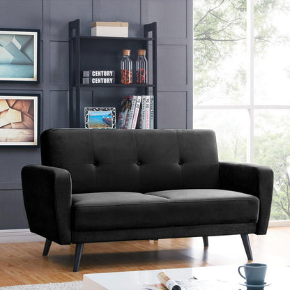 Esben 2-Seater Velvet Sofa Bed in Black, displaying a mid-century modern style, is showcased in a bright living room with a coffee table, shelving unit, and abstract wall art.