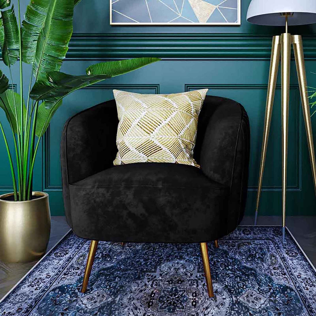 Evelyn Curved Velvet Sofa Accent Chair in Black with gold-toned legs, cream-gold geometric pillow, set against a teal wall, complemented by a tripod lamp, blue rug, and banana-leaf plant.