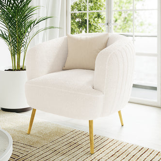 Evelyn Curved Boucle Accent Chair in Cream White features a boucle-upholstered design with softly rounded arms, brushed brass tapered legs, and a beige throw pillow, set in a sunlit, minimalist living space.