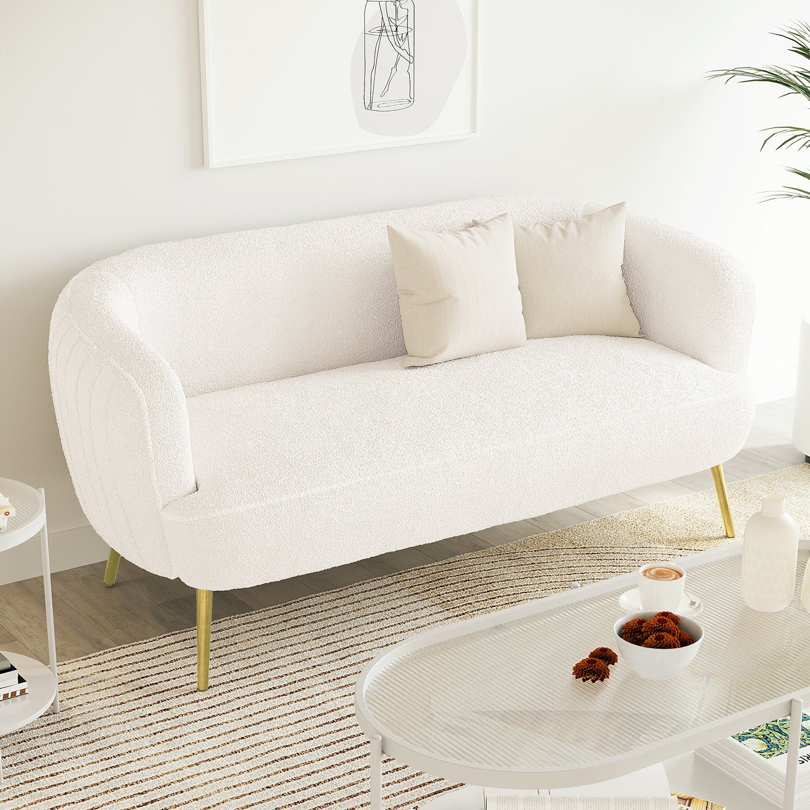 Evelyn 2 Seater Curved Boucle Sofa in Cream White, featuring a low, elegant design with slim brass-tone legs, adorned with two linen cushions, set in a minimalist Scandinavian-style living area.
