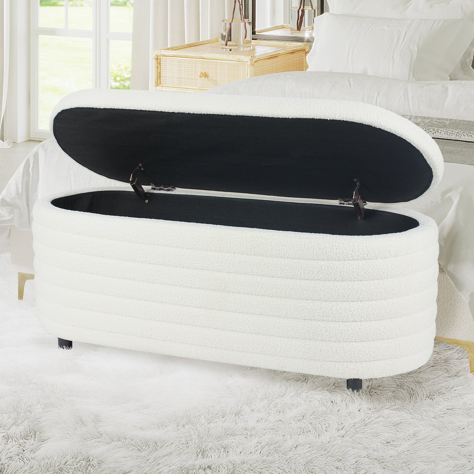 Hartwin 114cm Boucle Ottoman with Storage - Cream White, featuring a white upholstered lift-top design at a bed's foot, open to show a black-lined storage space for bedroom items.