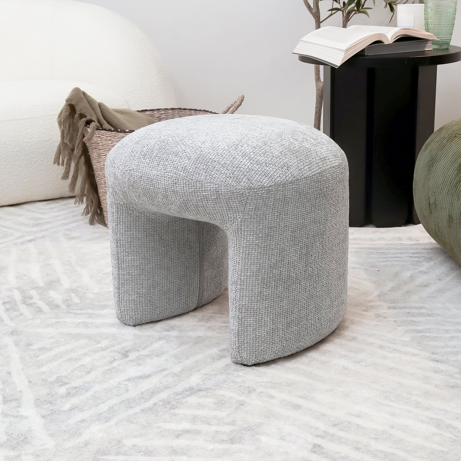 Hirokoz Chenille Ottoman Stool in Warm Grey, showcasing its plush chenille fabric and sturdy wood frame. The stool is depicted as a versatile piece for various indoor settings.
