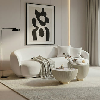 Janelle 213cm Curved Bouclé 3.5-Seater Sofa in Cream White, featuring plush throw pillows, a beige knitted blanket, and a solid wood frame, set in a minimalist living area.