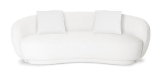 White bouclé curved sofa with two matching throw cushions against a plain white studio background.
