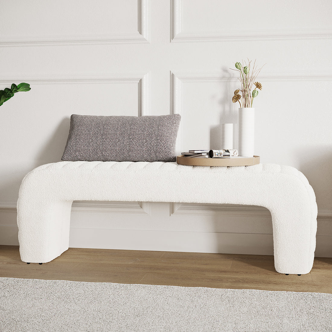 Josie Curved Boucle Fabric Bench Seat in Cream White features a U-shaped design with a textured gray lumbar pillow and a round wooden tray with vases and papers.