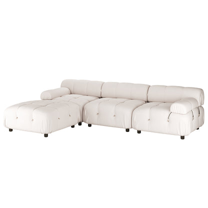 Keila 3 Seater Modular Tufted Sofa with Ottoman in Cream, featuring richly padded, button-tufted design, L-shaped configuration with chaise, armless benches, rolled armrest, and short black feet.