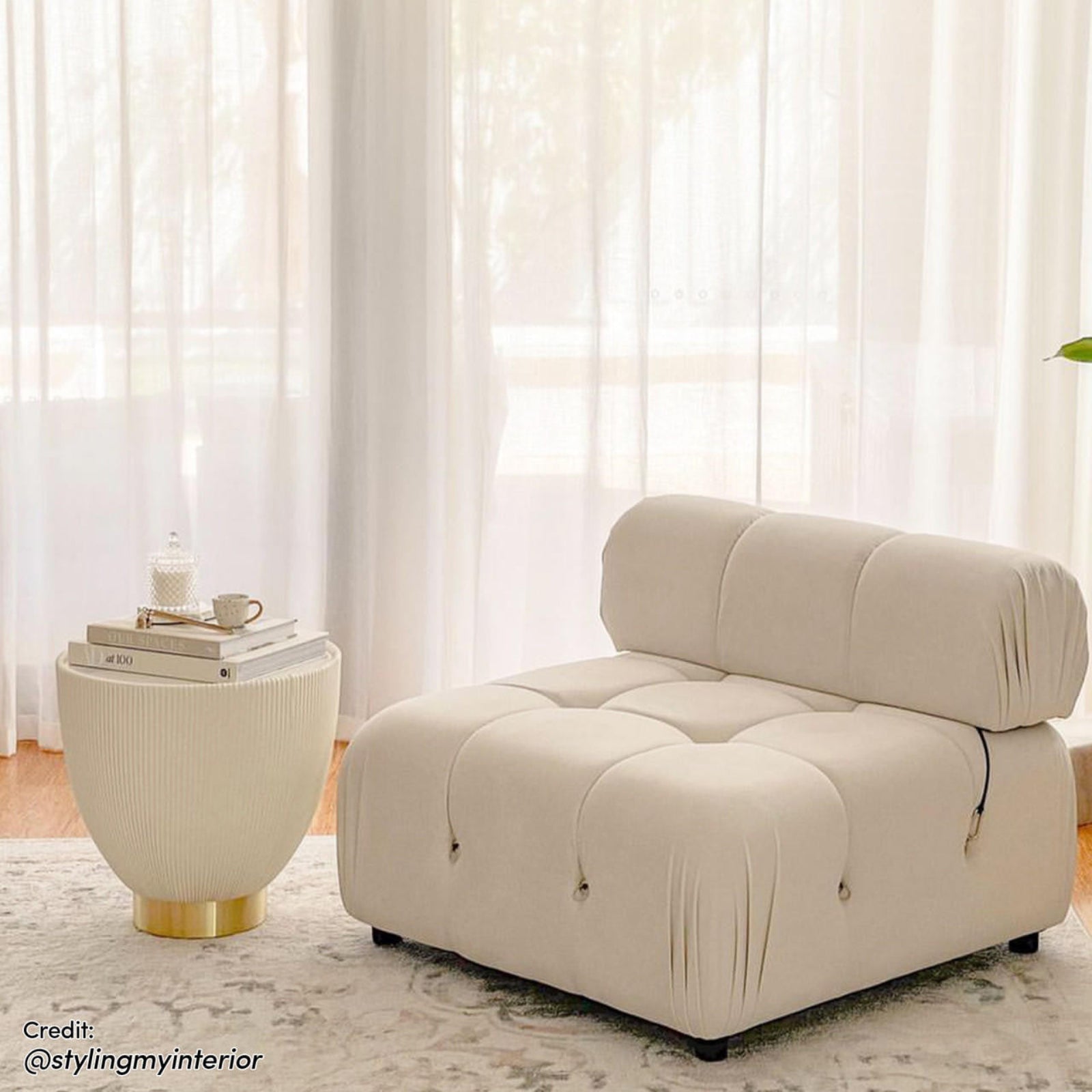Keila Modular Tufted Single Sofa in Cream Velvet with plush quilted surface, thick padded back cushion, sits by a cream ribbed side-table on a subtle patterned rug in softly lit room.