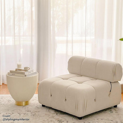Keila Modular Tufted Single Sofa in Cream Velvet with plush quilted surface, thick padded back cushion, sits by a cream ribbed side-table on a subtle patterned rug in softly lit room.