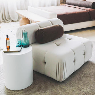 Keila Modular Tufted Single Sofa in Cream Velvet, featuring a low tufted design with an off-white fabric and cylindrical bolster pillow, elegantly showcased in a minimalist interior setting.