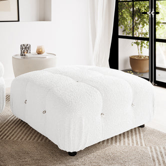 Keila Modular Tufted Boucle Ottoman in Cream White, featuring tufted channels and metal ring accents, placed on a neutral rug in a minimalist living room with a ribbed side table and sheer curtains.