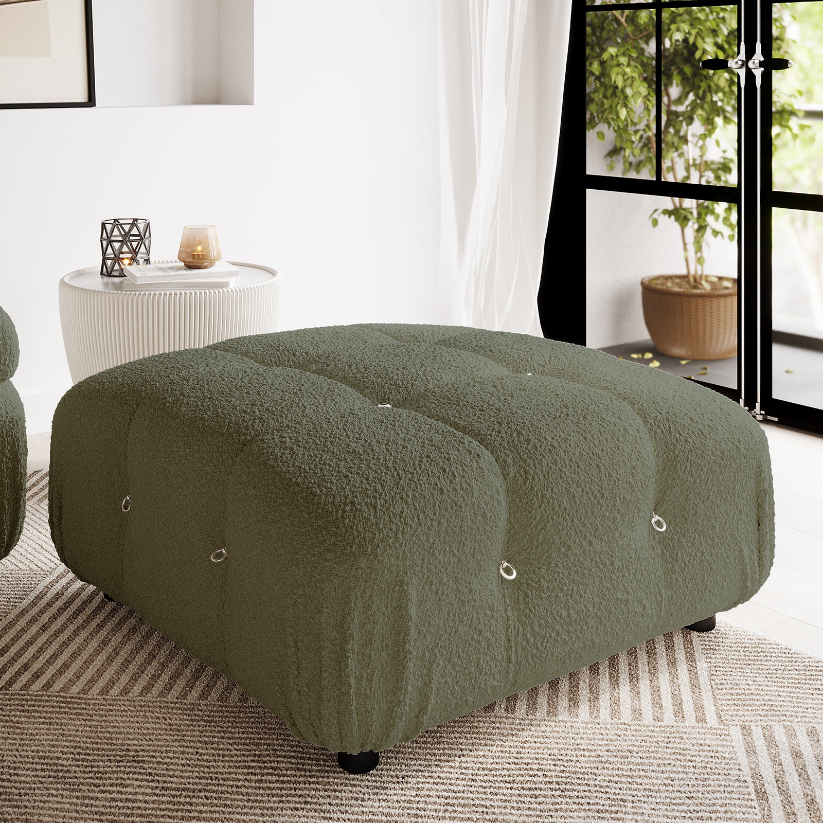 Keila Modular Tufted Boucle Ottoman in Green, featuring deep olive-green boucle upholstery, tufted nine-section design, and metal ring details, centered on a striped rug with a side table nearby.
