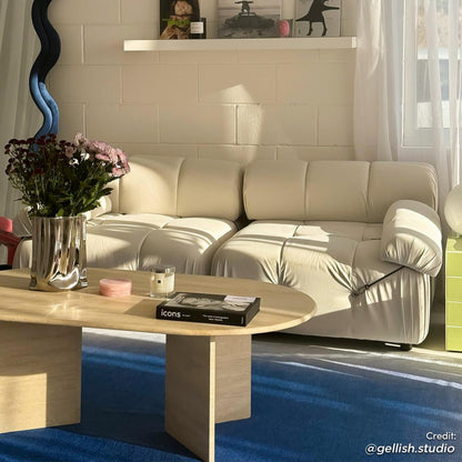 Keila 2 Seater Modular Tufted Sofa Set in cream velvet, nestled in a sunlit corner with a travertine coffee table, sculptural vase, and deep blue rug, exuding elegance and comfort.