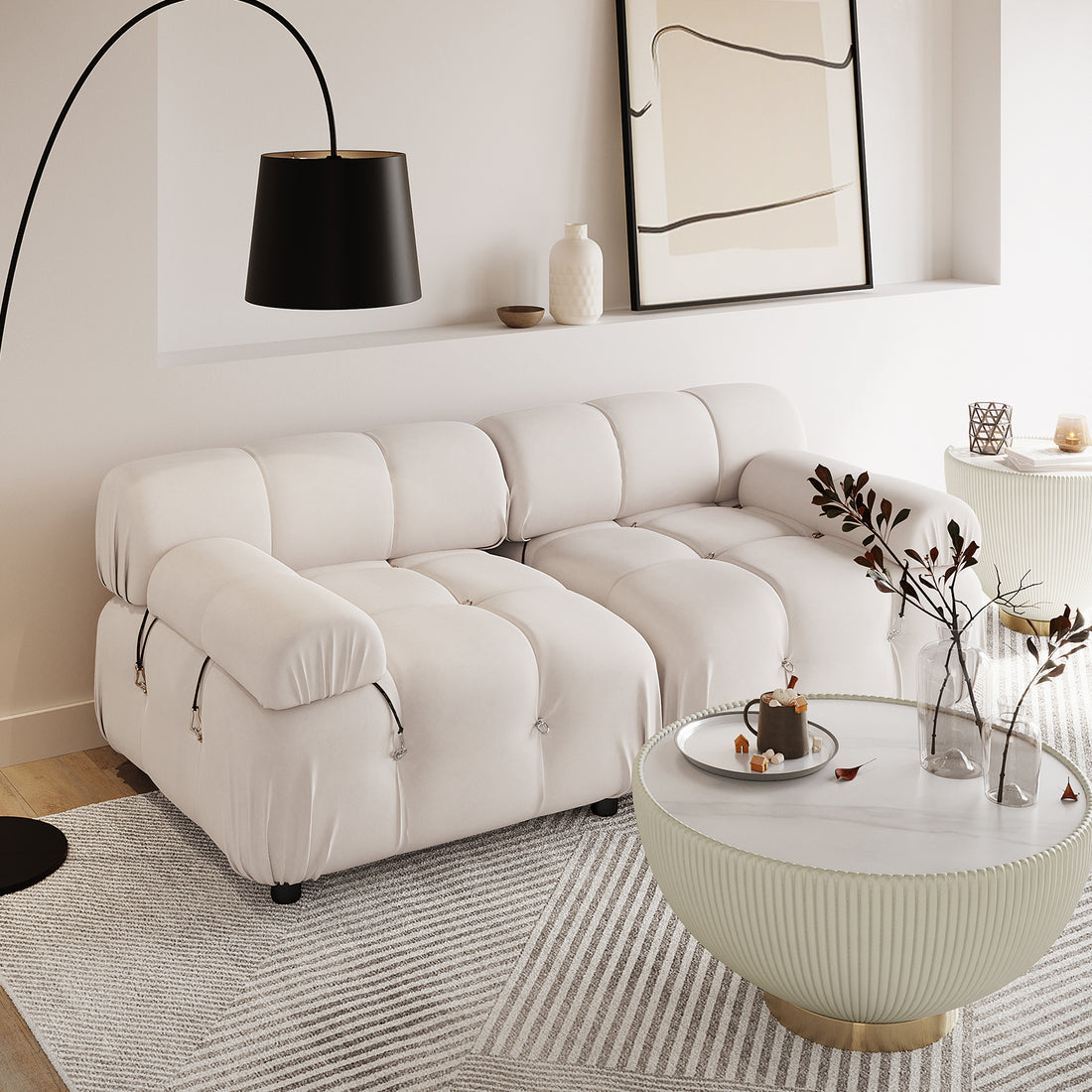 Keila 2 Seater Modular Tufted Sofa Set in Cream Velvet sits in a minimalist living room, paired with a curved floor lamp, ribbed coffee table, and geometric rug, exuding contemporary elegance.