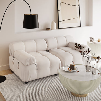 Keila 2 Seater Modular Tufted Sofa Set in Cream Velvet sits in a minimalist living room, paired with a curved floor lamp, ribbed coffee table, and geometric rug, exuding contemporary elegance.
