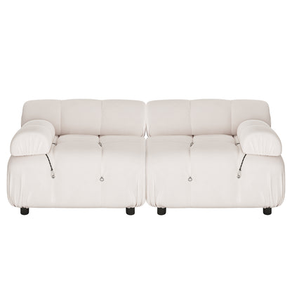 Keila 2 Seater Modular Tufted Sofa Set in Cream Velvet features a low-slung, puffy silhouette with tufted cushions, wide padded armrests, and short dark legs, exuding a contemporary, cozy charm.