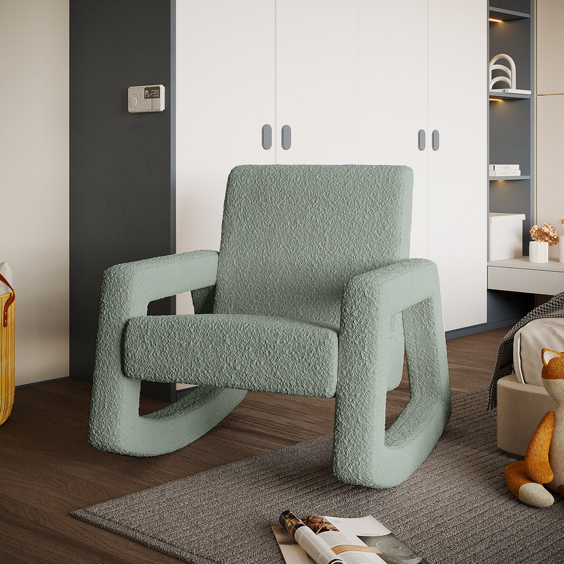 Ligeia Boucle Padded Rocking Chair in Mint Green on dark wood floor with white storage wall and decorative shelf behind, woven basket, open magazine, and plush fox toy nearby.